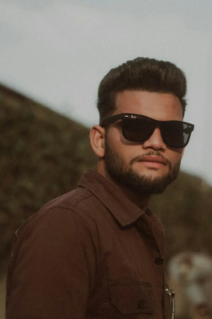 A man wearing sunglasses and a brown shirt